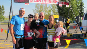 11.92KM Top Female Winner Alanna Handley poses with Proud Family at Finish Line